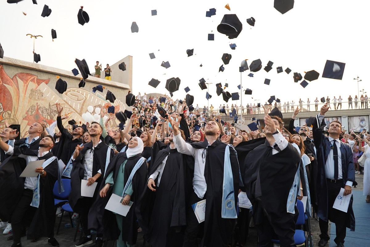 Studentë duke hedhur kësulën e diplomimit, foto nga UNT